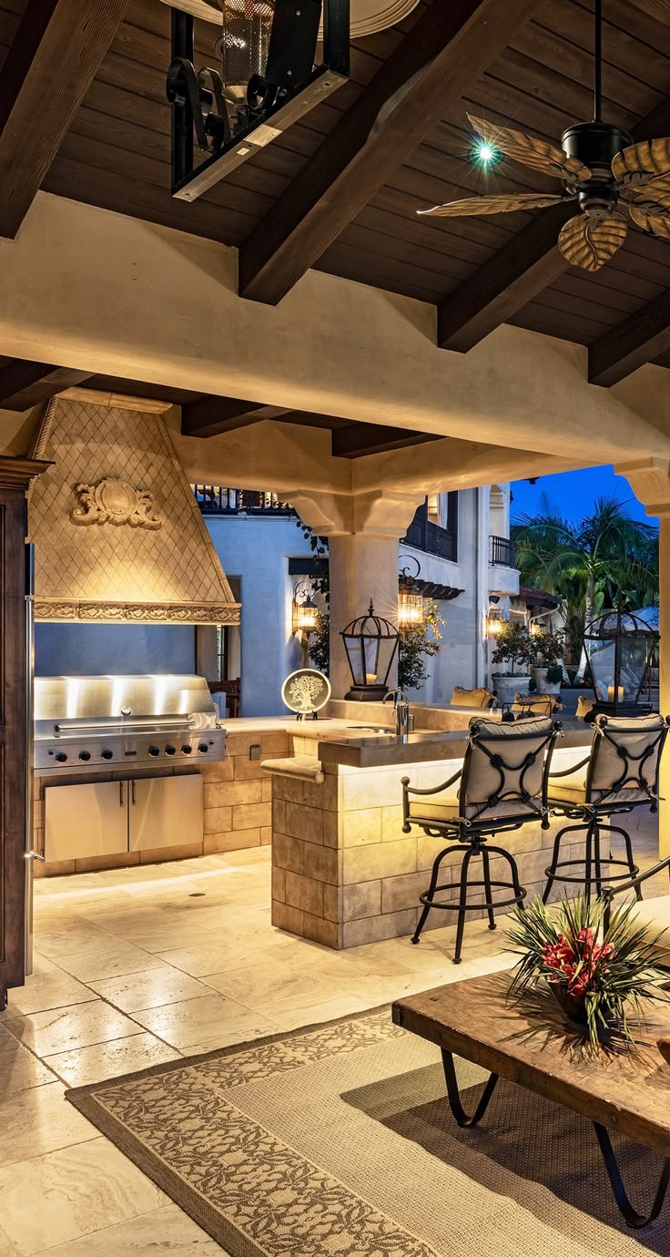 an outdoor kitchen and dining area is lit up at night with lights on the ceiling