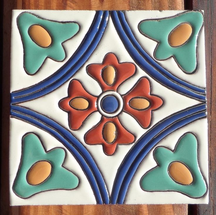 a close up of a decorative tile on a wooden surface