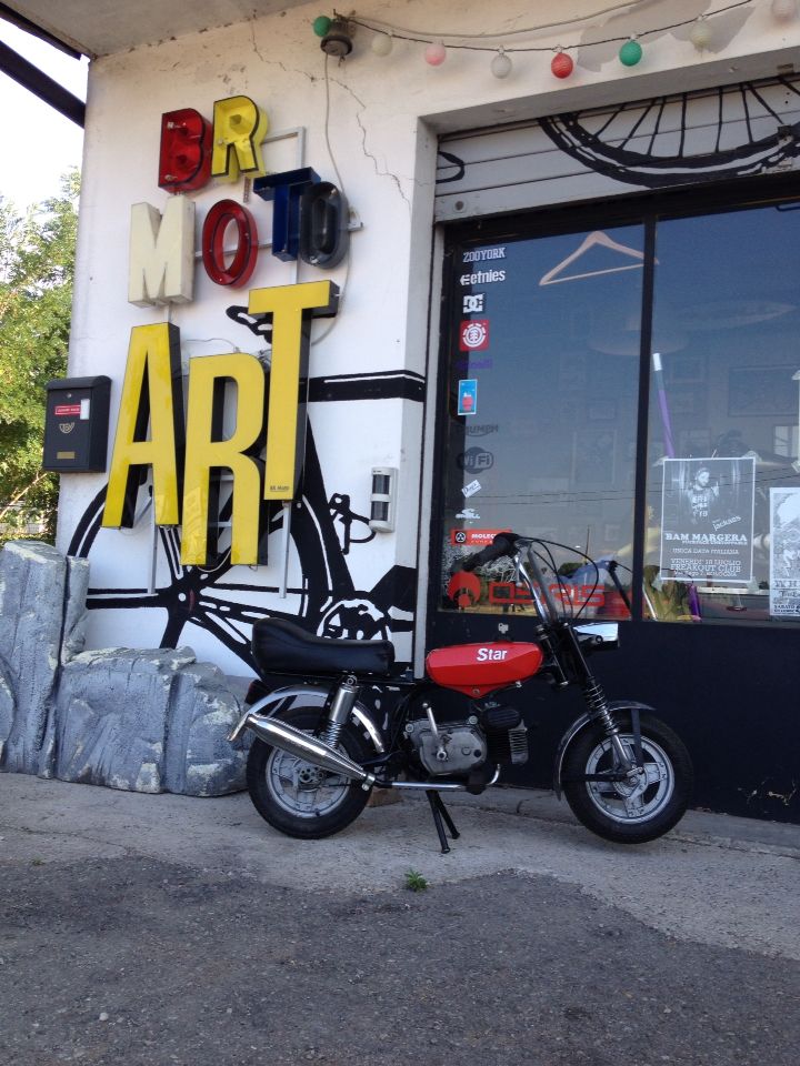 a motorcycle parked in front of a building with a sign that says art on it