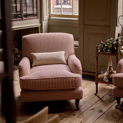 two chairs and a table in a room with wood flooring, one chair has pink striped upholster