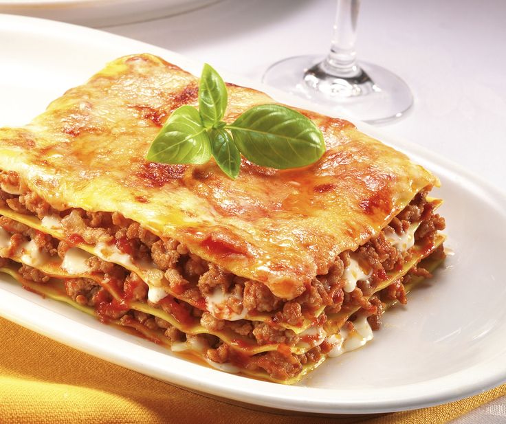 lasagna casserole with meat, cheese and tomato sauce on white plate