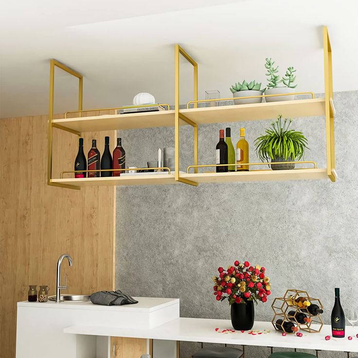 a kitchen counter with bottles and flowers on the top shelf, next to a sink