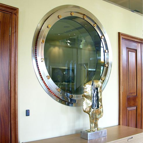 a large mirror on the wall above a wooden table with a statue in front of it