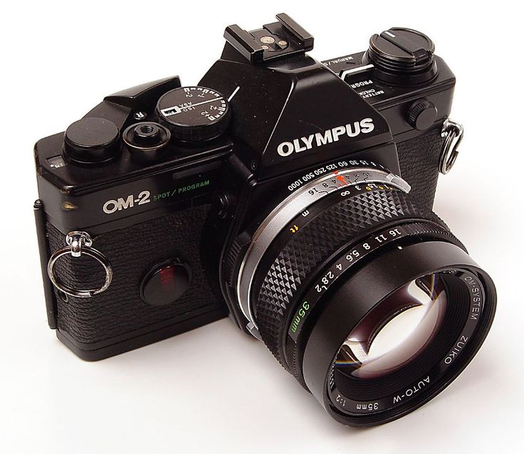 an old style camera sitting on top of a white surface with the lens up close