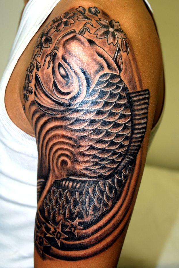 a man with a black and grey tattoo on his arm, holding a fish in it's mouth