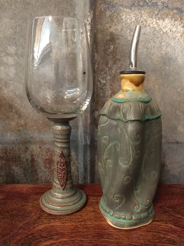 two wine glasses sitting next to each other on top of a wooden table in front of a stone wall