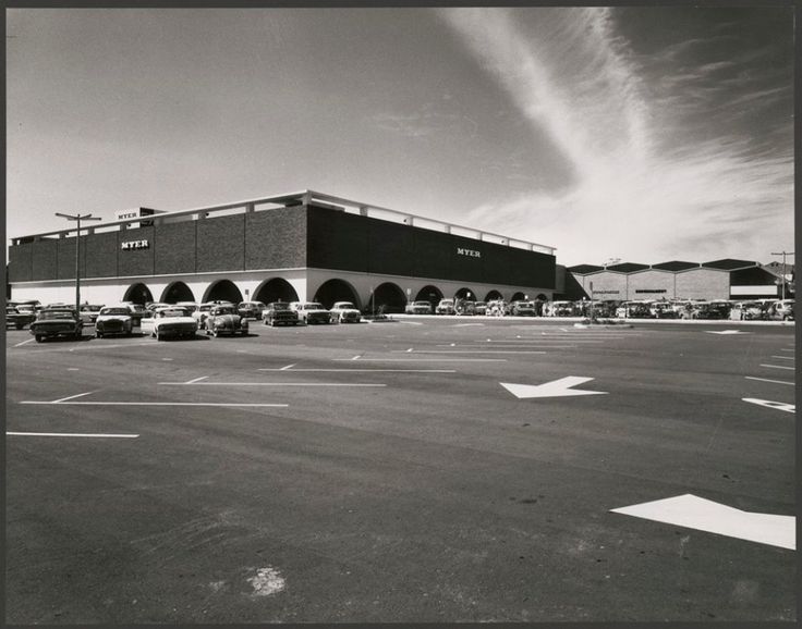 an empty parking lot in front of a store with cars parked on the side of it