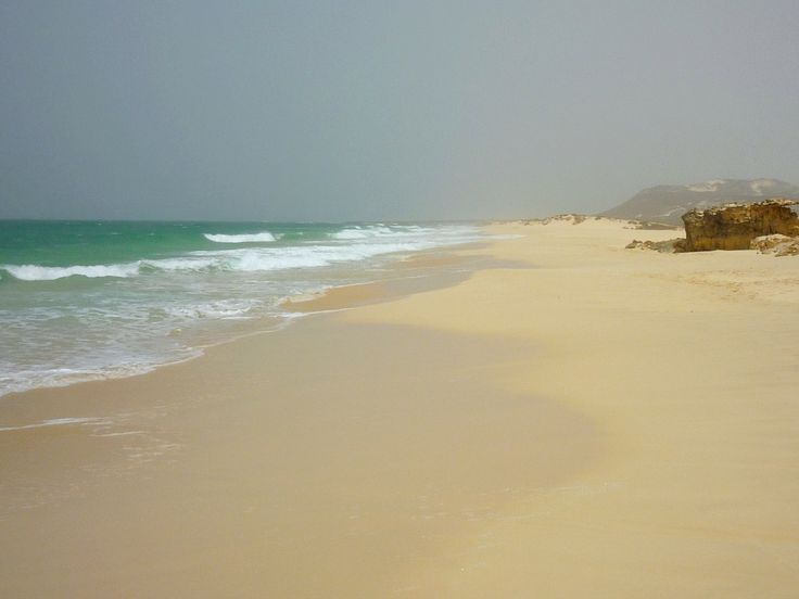 a sandy beach with waves coming in to shore