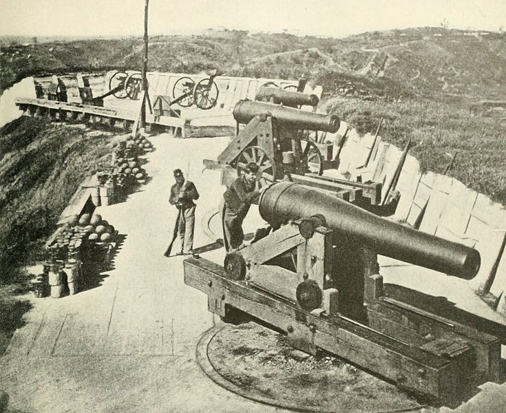 an old black and white photo of two men standing next to a cannon