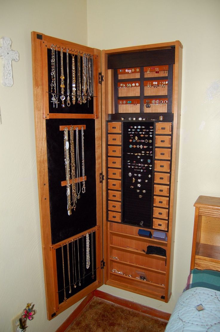 a wooden cabinet with many necklaces hanging from it's sides in a bedroom