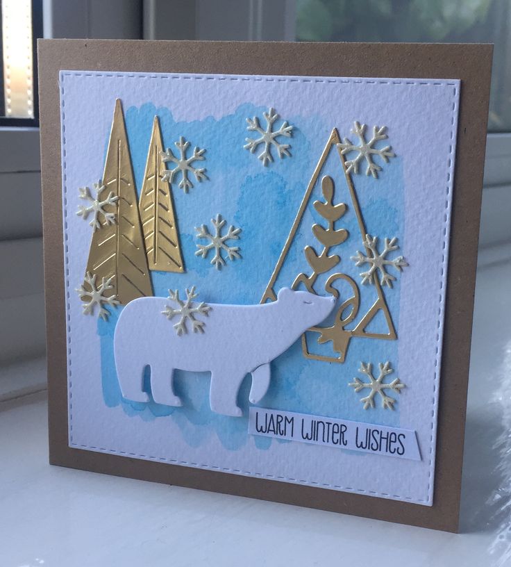 a polar bear card with snowflakes and trees in the background on a window sill