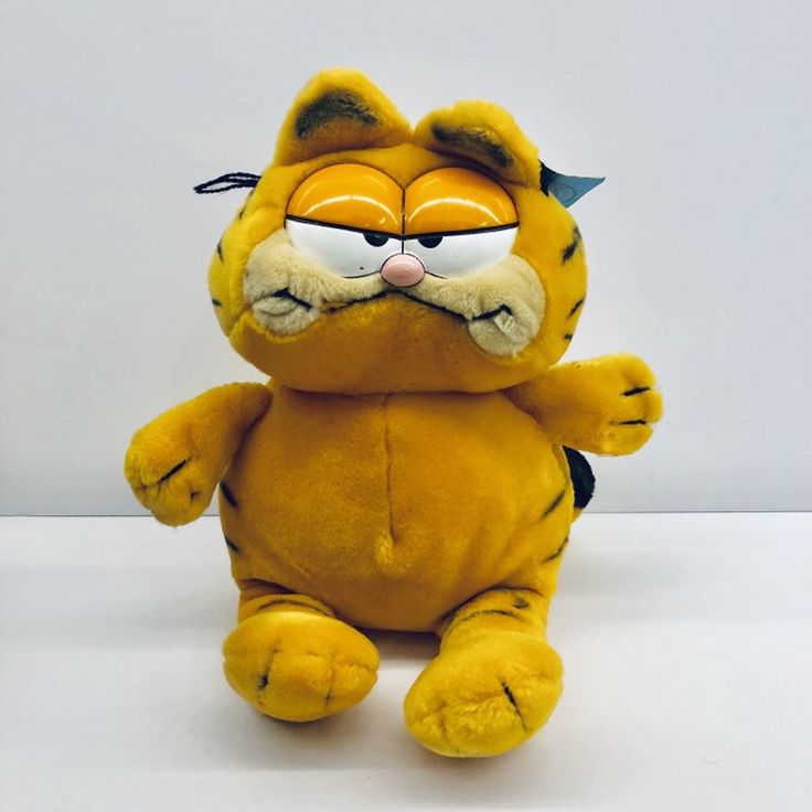 a yellow stuffed animal with glasses on it's face and eyes, sitting in front of a white background