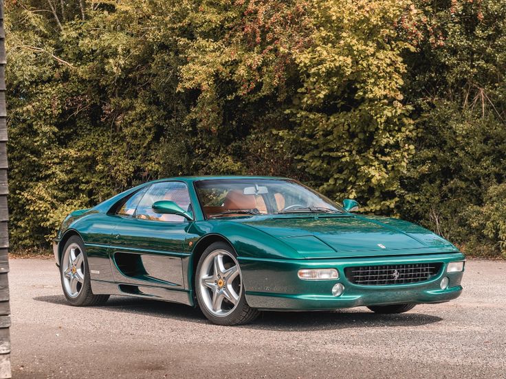 a green sports car parked in front of some trees