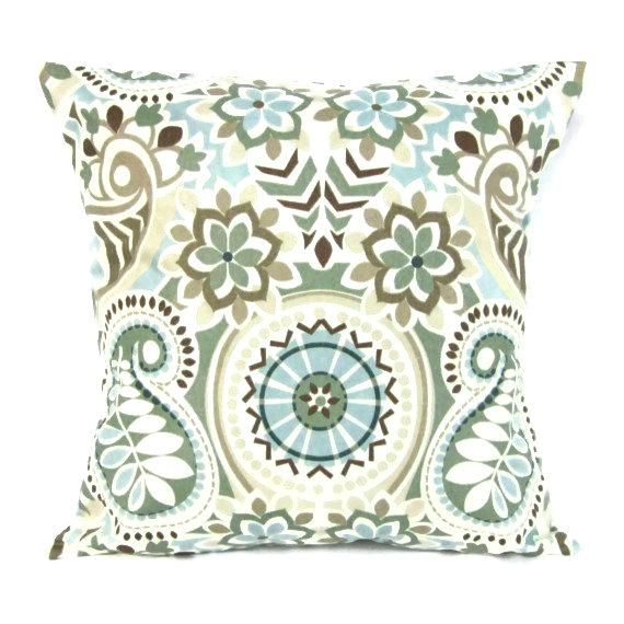 a decorative pillow with blue and green flowers on it, sitting on a white surface