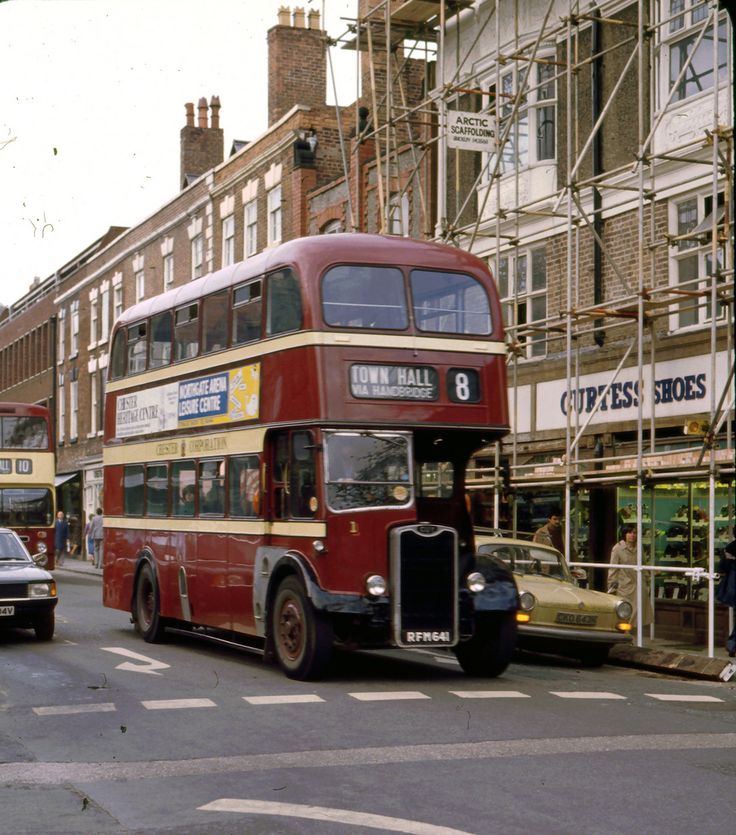 a double decker bus is driving down the street in front of other cars and buildings