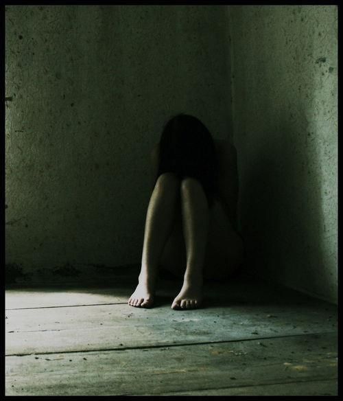 a woman sitting on the floor in an empty room with her hands under her head