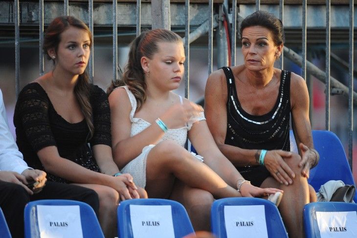 three women are sitting in the stands at a tennis match