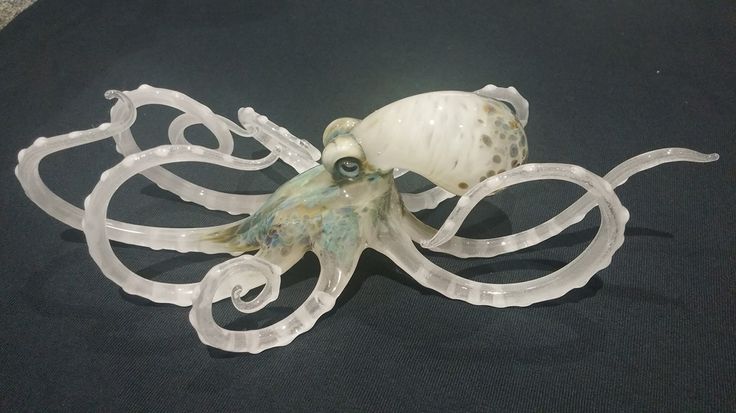 an octopus sculpture made out of plastic on a black tableclothed surface with white lights