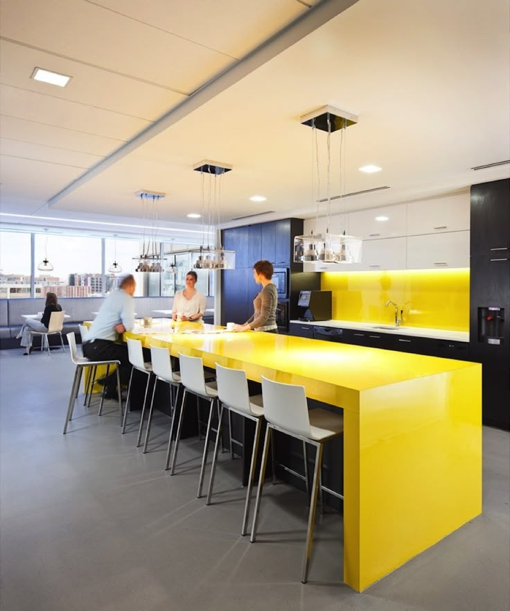 an empty office with yellow counter tops and white bar stools in front of it