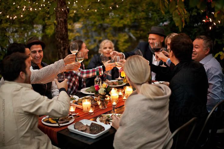 a group of people sitting around a table with food and drinks