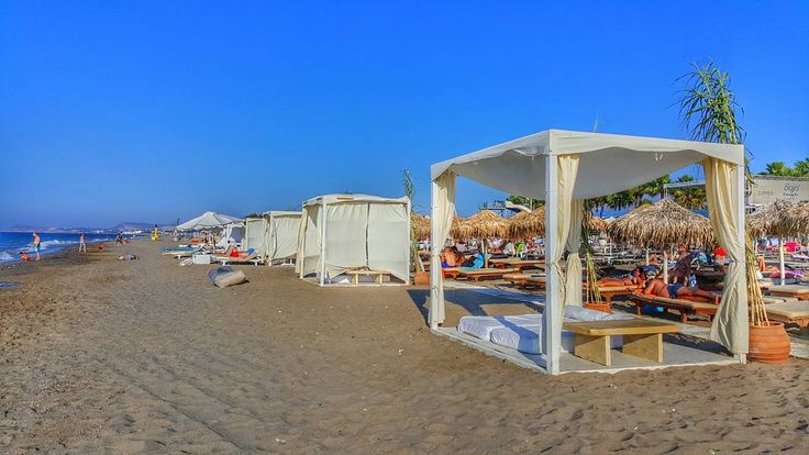 the beach is lined with umbrellas and beds for people to sit in them on