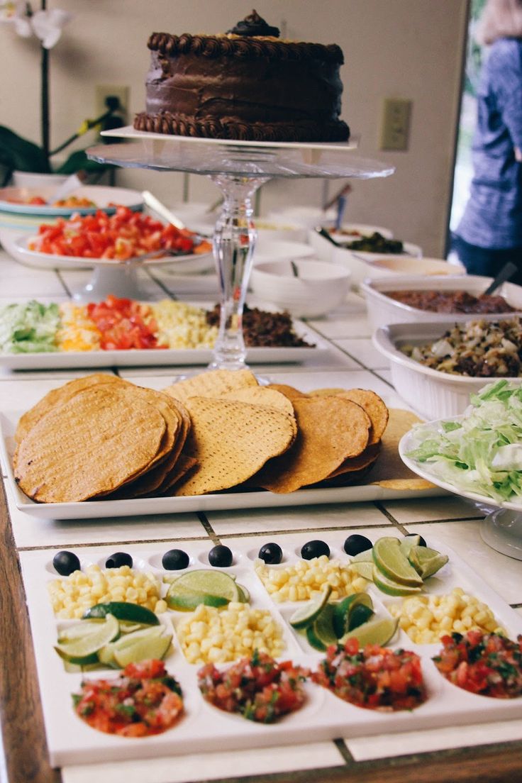 an assortment of food is displayed on a buffet table with plates and bowls full of salads