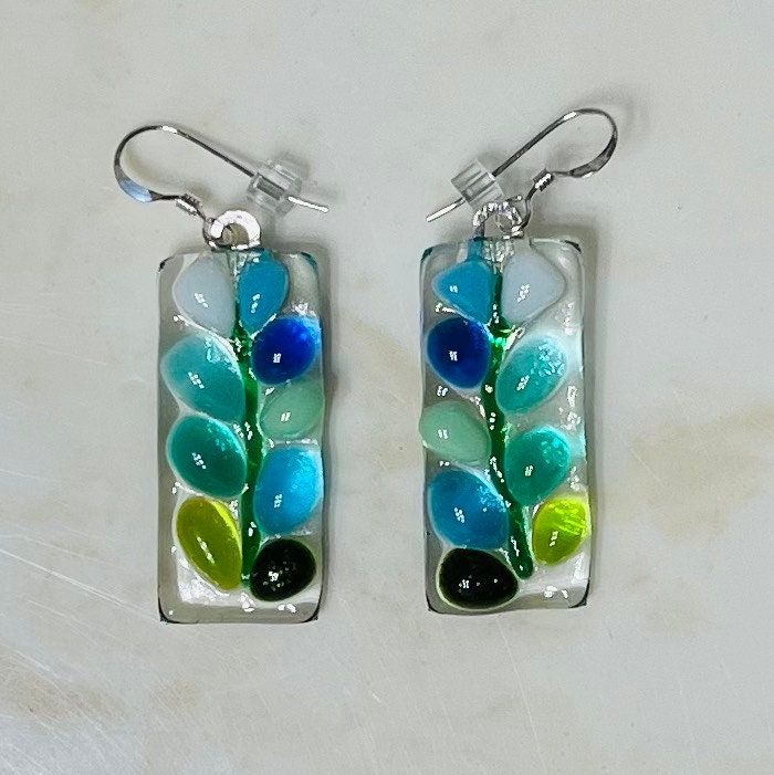 a pair of earrings with colorful glass beads and leaves hanging from the back of them