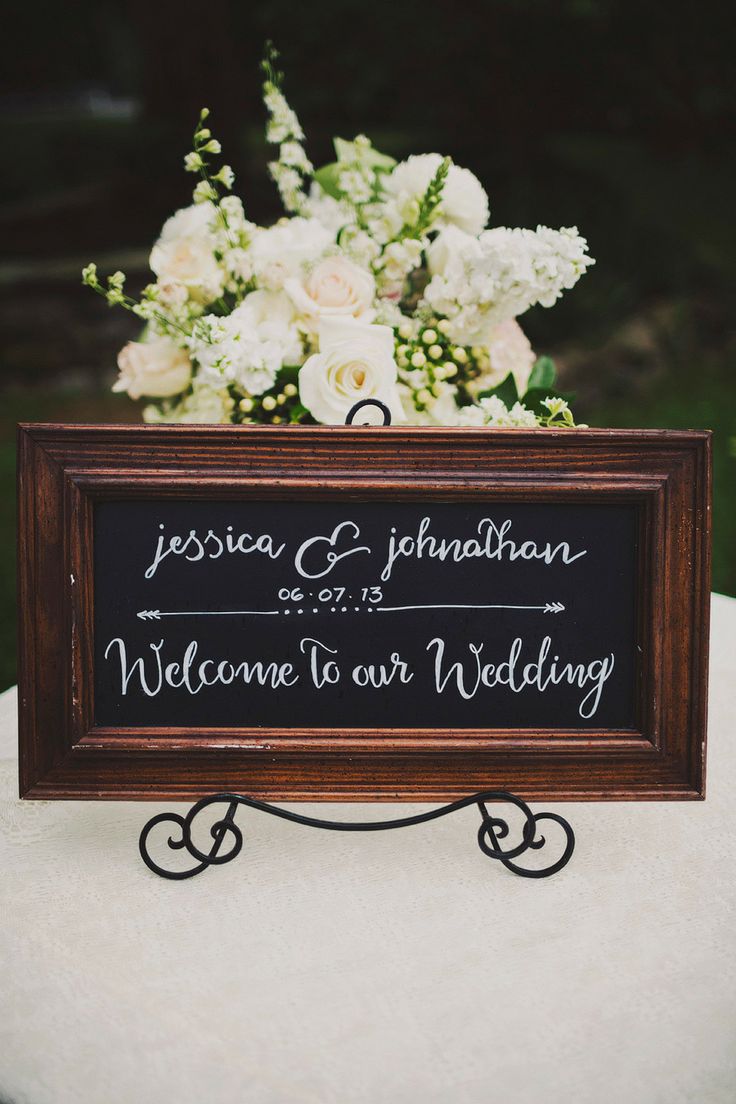 a wooden sign that says welcome to our wedding on top of a table with flowers