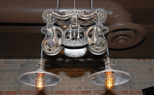 three light fixtures hanging from the ceiling in a room with brick walls and exposed ceilings