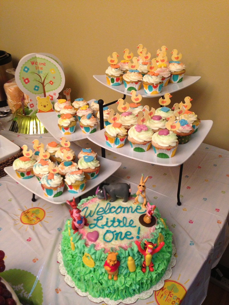 a table topped with lots of cupcakes covered in frosting and winnie the pooh decorations