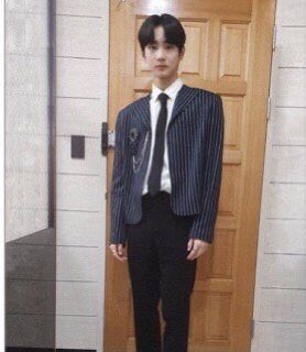 a young man wearing a suit and tie standing in front of a door