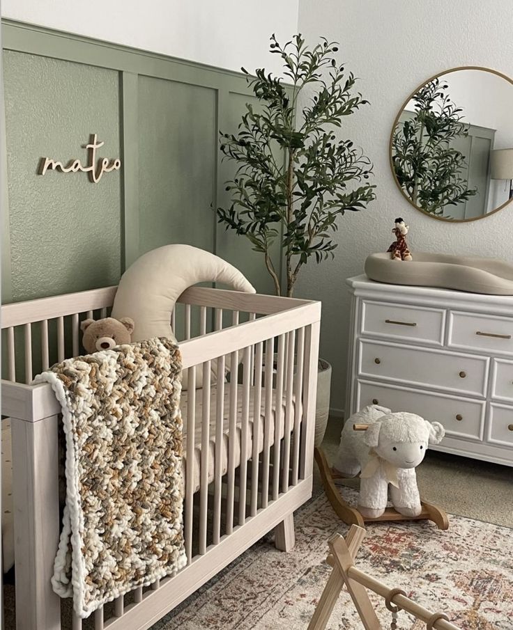 a baby's room with a crib, dressers and a tree in the corner