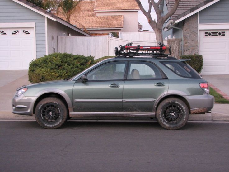 the car is parked on the side of the road with its roof rack strapped to it