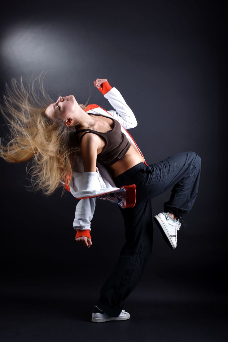 a woman is dancing in the air with her hair blowing back and feet behind her