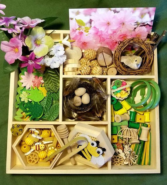 a wooden tray filled with lots of different types of crafts and flowers on top of a green table cloth