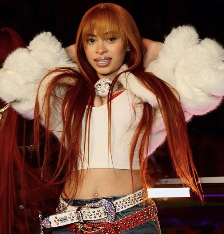 a woman with long red hair and big white wings on her head is posing for the camera