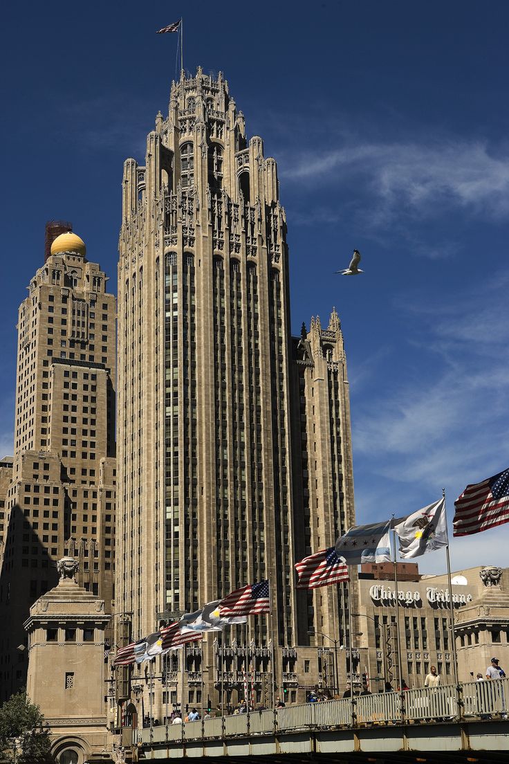 a large building with many flags flying in the air next to it and a bridge