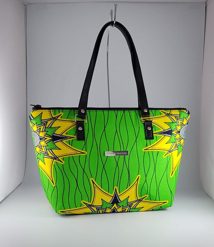 "\"Bag description:  This lovely bag is a perfect size for any occasion, with ample room for all your essentials when shopping, going to the office or on an evening out. Brighten up your day with this green and yellow vibrant bag and change the mood around you.   This tote bag is a combination of Ankara African fabric and faux leather, fully lined waterproof canvas fabrics. The handles are long enough to fit comfortably on the shoulder or held by hand. Internally, this bag is fully lined with waterproof canvas and zippered pocket which fits your phone or other valuables. This bag is closed with a durable zip. Bag Style: Tote Fabric: African Wax Print Fabric - Ankara green and yellow print fabric. 100% Cotton Lining: Waterproof canvas Hardware: Chrome  Handles: 24 inches in black faux leath Star Tote Bag, Green Star, African Wax Print, Yellow Print, Wax Print, African Fabric, Green And Yellow, Black Faux Leather, African Print