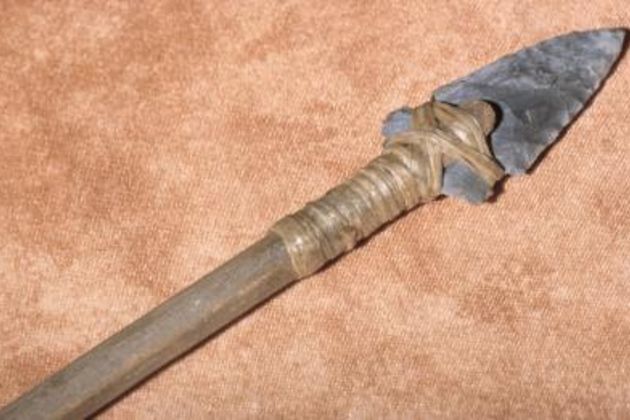 an old metal knife with a wooden handle on a brown carpeted floor in front of a tan background