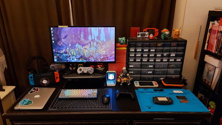 a desk with a computer monitor, laptop and other items on it in front of a window