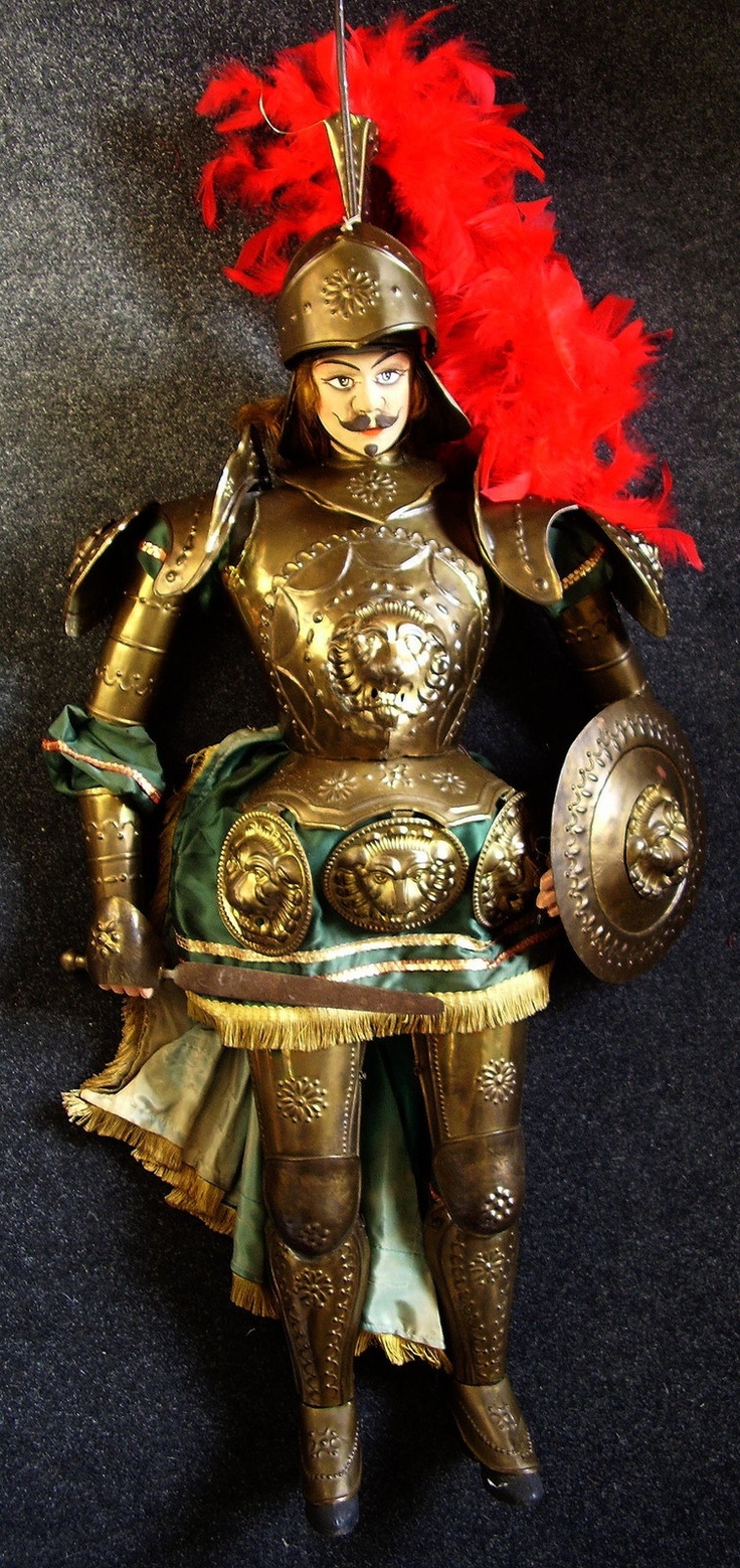 a statue of a woman in armor with red feathers on her head