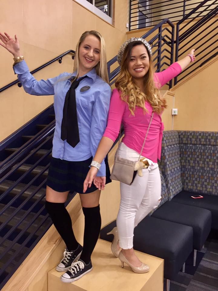 two young women dressed in school uniforms posing for a photo on the stairs with their arms outstretched