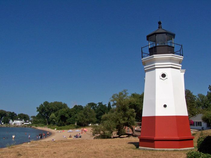 a red and white light house sitting on top of a sandy beach