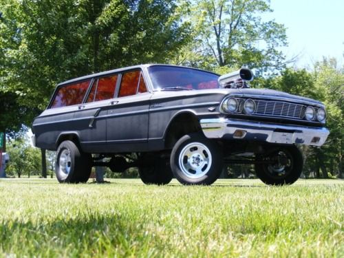 an old station wagon is parked in the grass