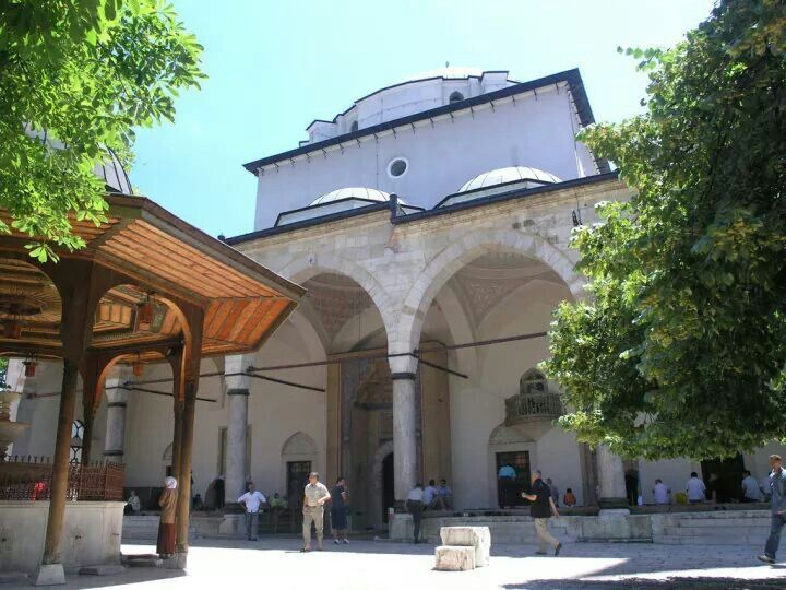 people are walking around in front of an old building with arches and pillars on the sides