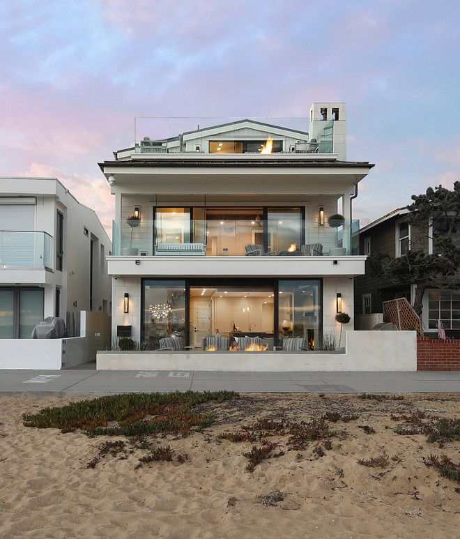 a large white house sitting on top of a sandy beach