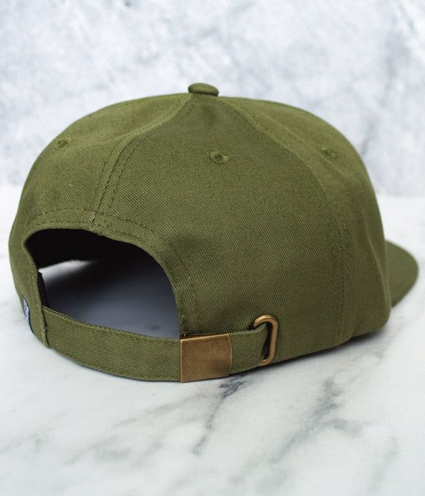 Rep Sugar Land in style with this classic cotton twill hat, in crisp Olive color. Featuring 6-panel construction, this hat is decorated with our vintage emblem design embossed on round leather patch and finished with contrast stitch. With a flat bill and breathable material, it's just the right hat to have for hot summer days. Fitted with a brass buckle on the back strap for easy size adjustment. Also available in Atlantic Blue color. Military Cotton Snapback Hat, Classic Snapback Hat With Logo Patch, Military Style Cotton Snapback Hat, Military-style Cotton Snapback Hat, Classic Flat Cap Trucker Hat For Streetwear, Canvas Snapback Hat With Embroidered Logo, Classic Solid Color Trucker Hat Snapback, Classic Solid Color Snapback Trucker Hat, Vintage Canvas Baseball Cap With Curved Brim