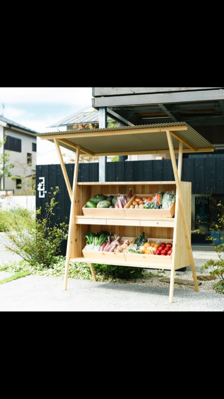 an outdoor vegetable stand with lots of vegetables on the shelf and in front of it