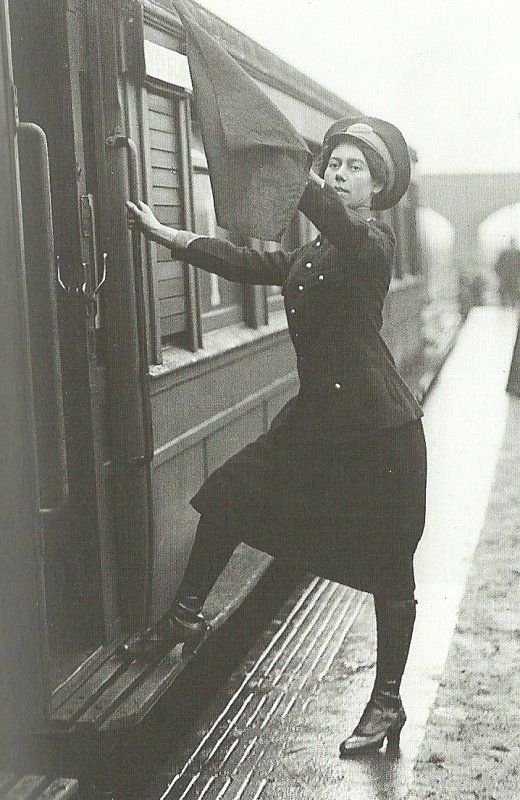 a woman leaning on the side of a train door while wearing a hat and coat