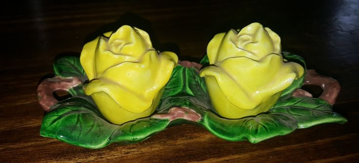 two yellow roses sitting on top of green leaves